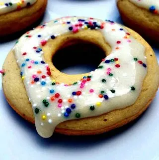 4 vanilla protein donuts on a white plate with sprinkles