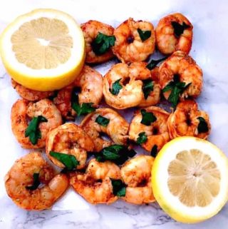 spicy smoky shrimp on a white surface with sliced lemons