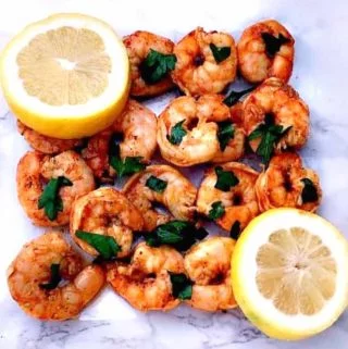 spicy smoky shrimp on a white surface with sliced lemons