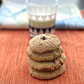 4 peanut butter dark chocolate chip protein cookies stacked in front of glass of milk