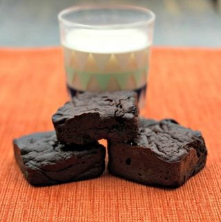 3 brownies stacked in front of a glass of milk