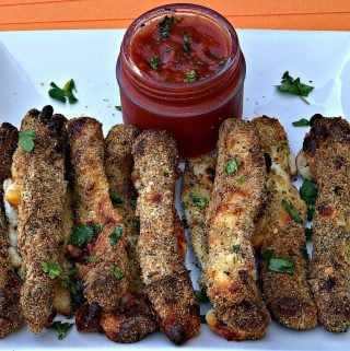 Air Fried Mozzarella Cheese Sticks on a white plate with a jar of marinara sauce