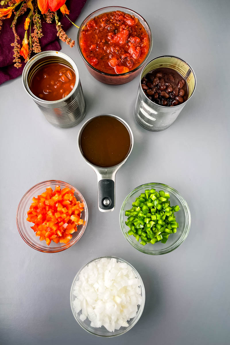 chili beans, black beans, beef broth, chopped green peppers, chopped red peppers, fire roasted tomatoes, and chopped onions in separate bowls