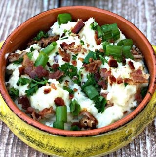 mashed potatoes in a yellow bowl with green onions