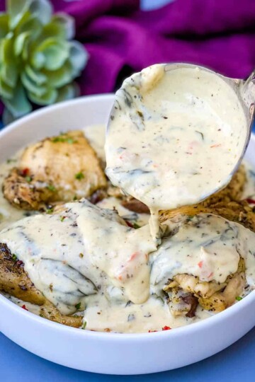 Instant Pot Low-Carb Creamy Garlic Tuscan Chicken Thighs in creamy sauce with parsley in a white bowl