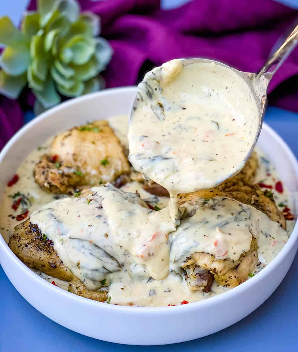 Instant Pot Low-Carb Creamy Garlic Tuscan Chicken Thighs in creamy sauce with parsley in a white bowl