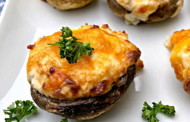 cooked stuffed mushroom with cheese on a white plate