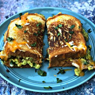 guacamole bacon grilled cheese sandwich cut in half on a blue plate