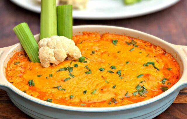 keto low carb buffalo chicken dip in a bowl, plate of celery and cauliflower