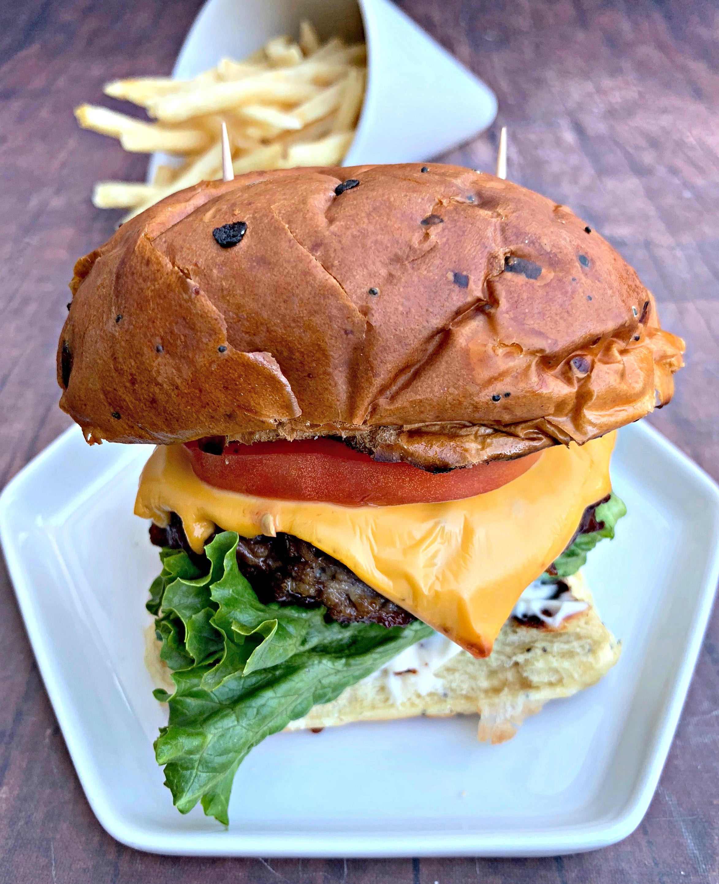 juicy air fryer cheeseburgers on a bun and white plate with fries