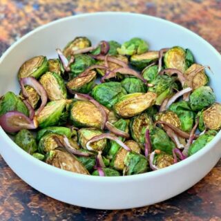 air fryer balsamic brussels sprouts with red onions in a white bowl