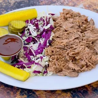 instant pot pulled pork on a plate with cabbage and pickles