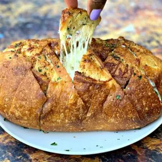 person pulling a piece of air fryer pull apart garlic cheese bread