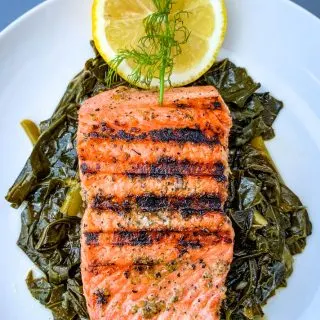 pan seared cast iron salmon on a white plate with greens