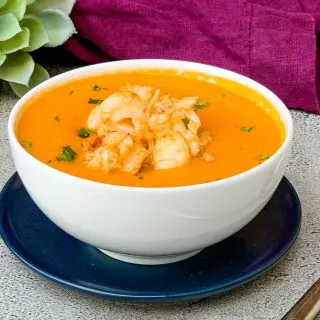 creamy homemade lobster bisque recipe in a white bowl with a purple towel