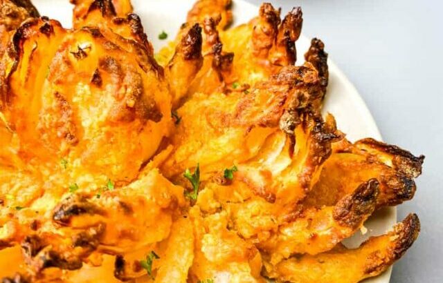 air fryer blooming onion on a plate with sliced lemons