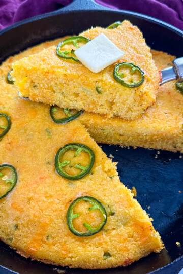 jalapeno cheddar cornbread with butter in a cast iron skillet