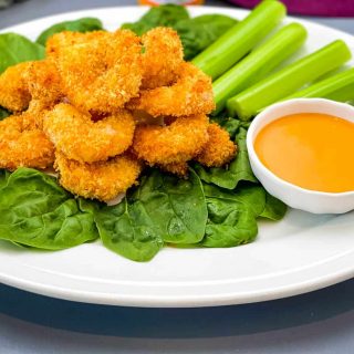 buffalo shrimp on a bed of lettuce with a bowl of buffalo sauce