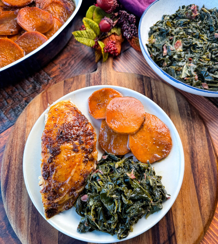 Cajun turkey on a plate with gravy, collard greens, and candied sweet potatoes