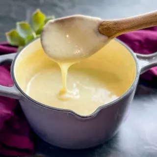 a wooden spoon of homemade cream of chicken soup over a saucepan