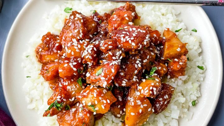 keto low carb orange chicken on a white plate with sesame seeds