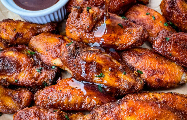 plate of keto low carb chicken wings being glazed with maple syrup