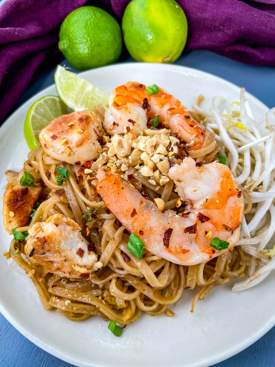 healthy pad thai with chicken, shrimp, bean sprouts, and lime on a white plate