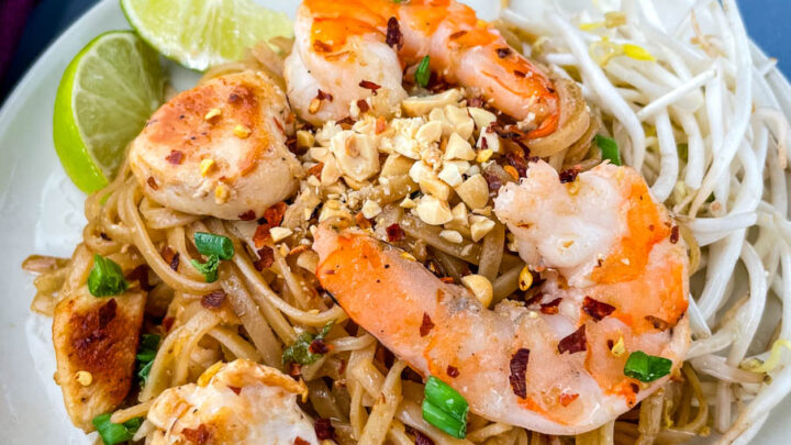 healthy pad thai with chicken, shrimp, bean sprouts, and lime on a white plate