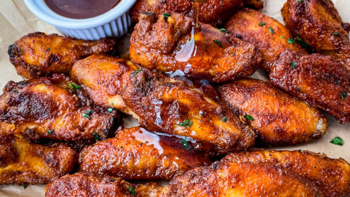 plate of keto low carb chicken wings being glazed with maple syrup