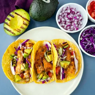 Blackened Fish Tacos on a plate with fresh avocado and cabbage