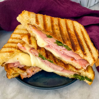 sliced ham and cheese panini sandwich on a plate