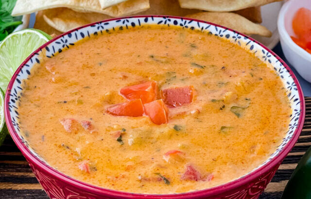 queso cheese dip in a red bowl with a plate of chips