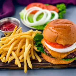 grilled cheeseburgers on a bun with a plate of fries