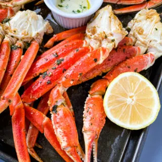 baked crab legs on a pan with lemon garlic butter