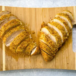 air fryer parmesan crusted chicken sliced on a bamboo cutting board