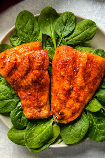 cooked indoor grilled salmon on a plate with fresh spinach