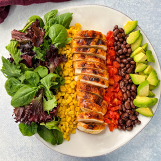 southwest salad with lettuce, corn, chicken, tomatoes, black beans, and avocado on a plate