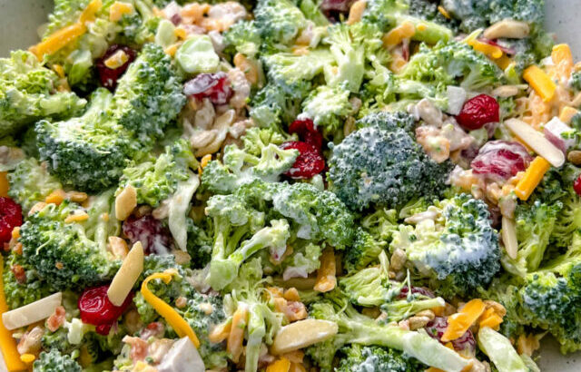 broccoli salad with cheese, bacon, and cranberries in a white bowl