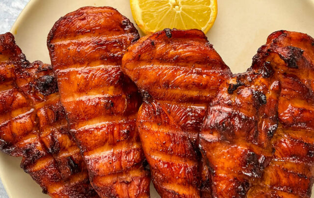 Traeger smoked chicken breasts on a plate with lemons