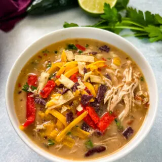 slow cooker chicken taco soup in a white bowl with tortilla strips and cheese