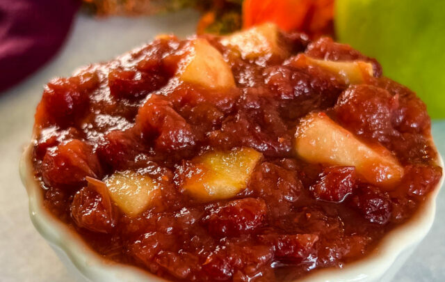 apple cranberry sauce in a white bowl with a fresh apple