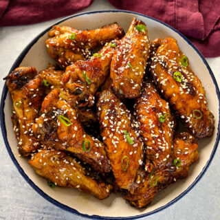 teriyaki chicken wings in a white and blue bowl with sesame seeds