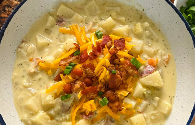 slow cooker loaded potato soup in a white bowl with bacon and cheese