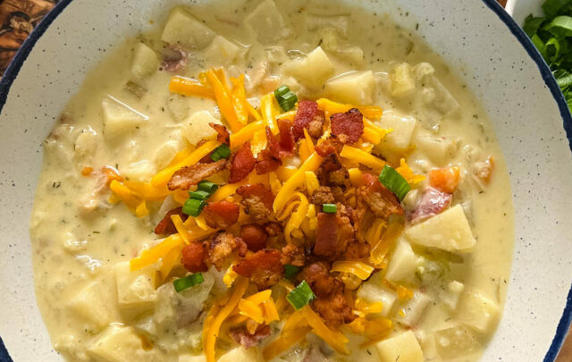 slow cooker loaded potato soup in a white bowl with bacon and cheese