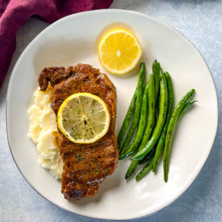 lemon pepper steak with lemon, mashed potatoes, and green beans