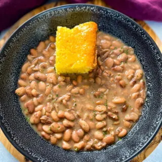 pinto beans, ham hocks, and cornbread in a black bowl