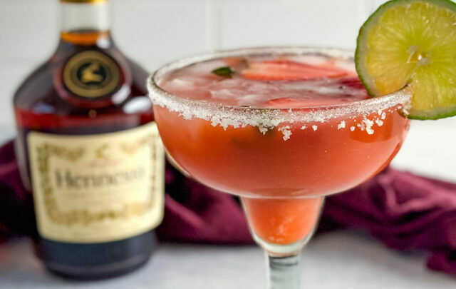 Hennessy margarita in a glass with strawberries and lime