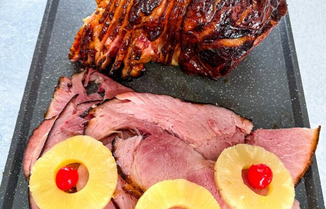 Traeger smoked ham sliced on a plate with pineapples and cherries