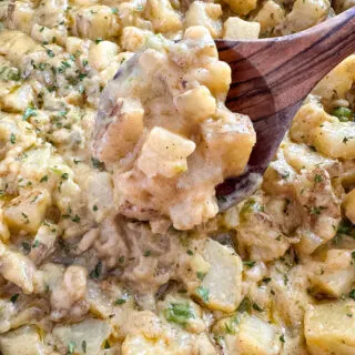 smothered potatoes with onions, peppers, and gravy in a cast iron skillet