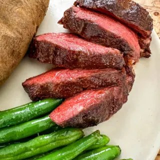 smoked filet mignon on a plate with green beans and a baked potato